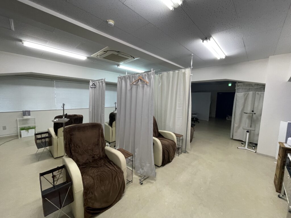 東京都品川区のクリニック内の内装工事完了後の様子。診察用椅子と、プライバシーに配慮したカーテン仕切りが設置された清潔感のある空間。