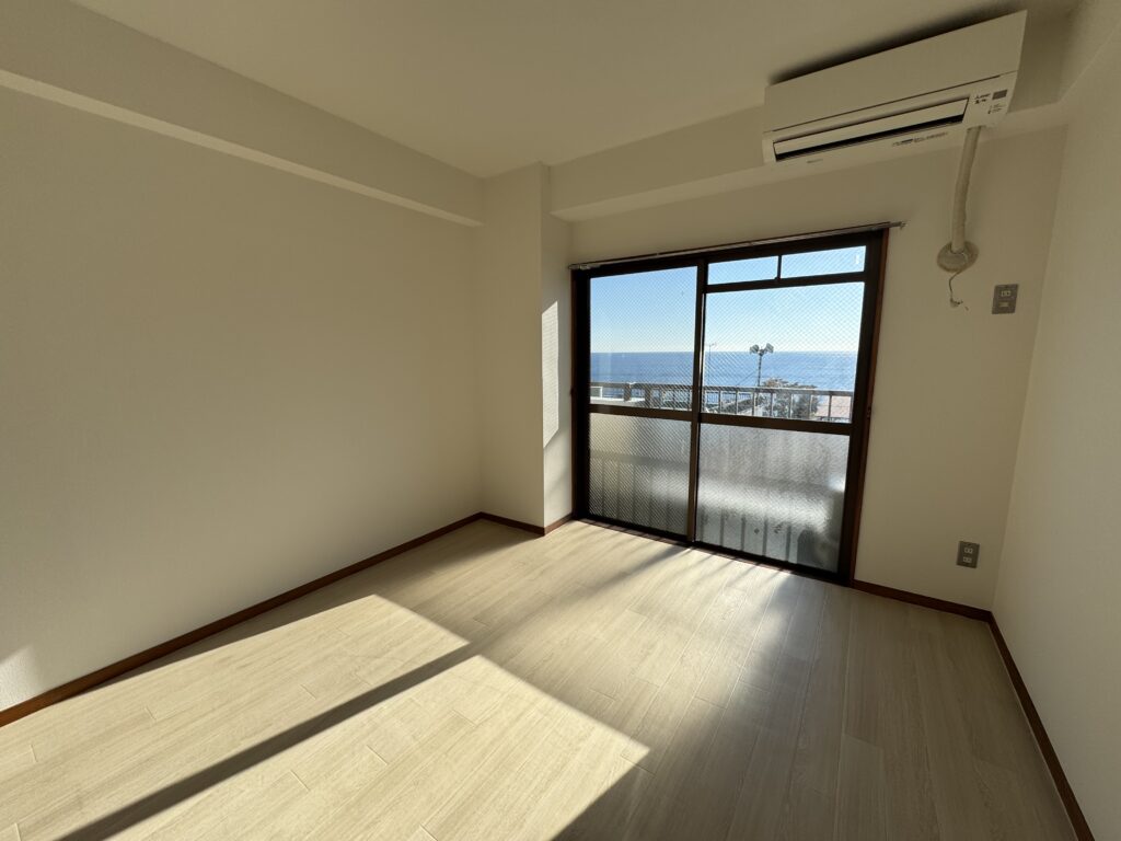 熱海市のマンションリフォーム施工例。窓から海が見える洋室のクロス張替えとクッションフロア（CF）施工後の様子。