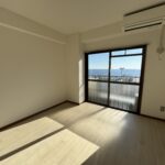 熱海市のマンションリフォーム施工例。窓から海が見える洋室のクロス張替えとクッションフロア（CF）施工後の様子。